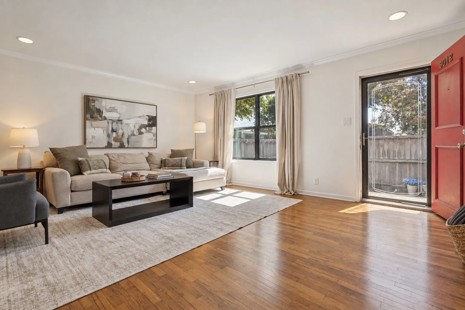 Recessed ceiling lighting, wood-finish flooring, white crown molding, and a solid red entry door with a screen door