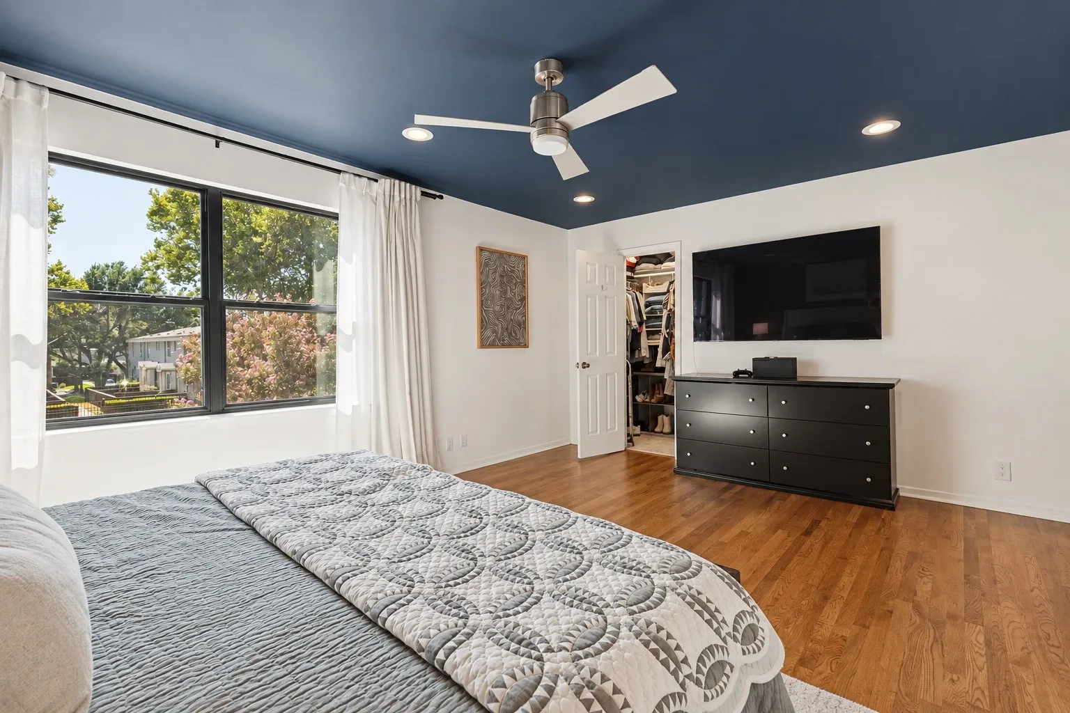 Hardwood flooring, recessed lighting, ceiling fan, large window, and walk-in closet
