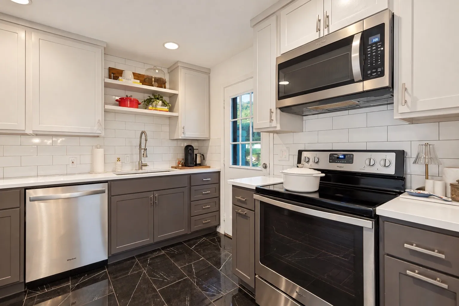 Two-tone cabinetry with stainless steel appliances, open shelving, and a tile backsplash