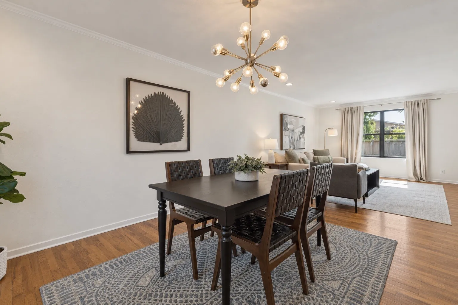 Wood-finish flooring throughout, crown molding, and a contemporary chandelier