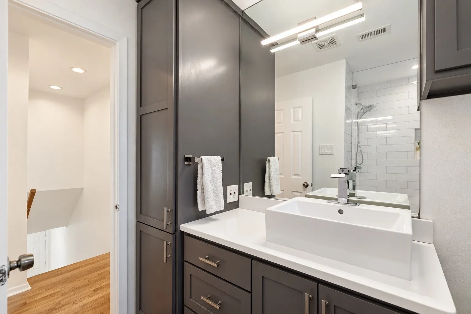 Vanity with a rectangular vessel sink, polished chrome faucet, white countertop, and dark gray cabinetry