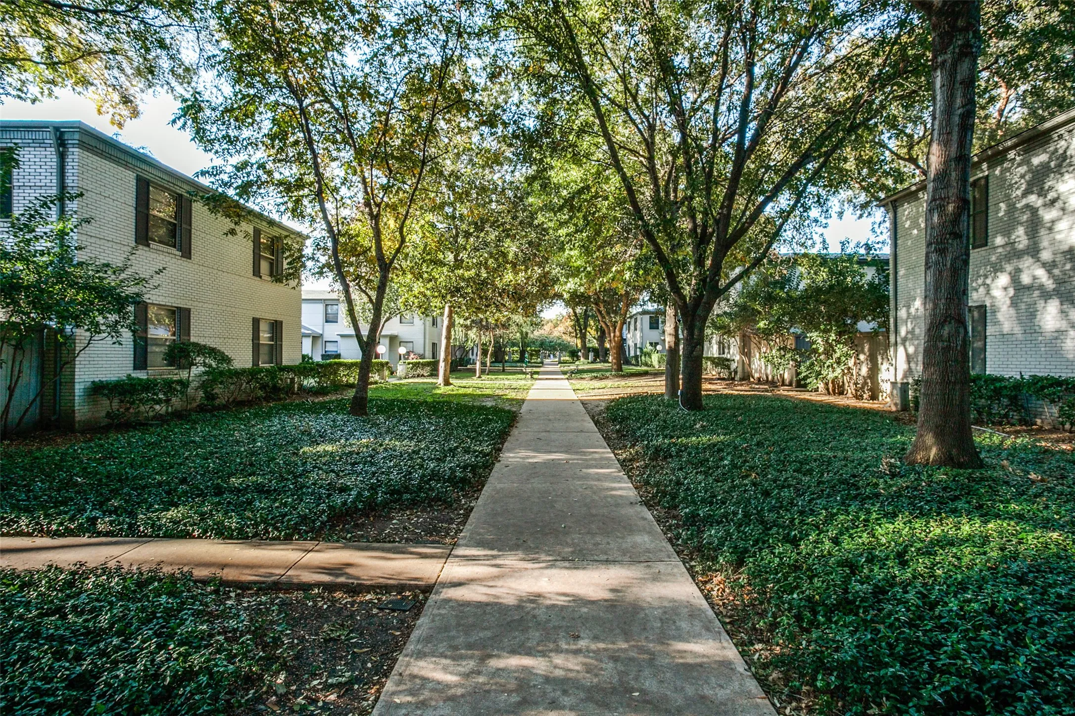 Landscaped grounds featuring mature trees and a concrete pathway