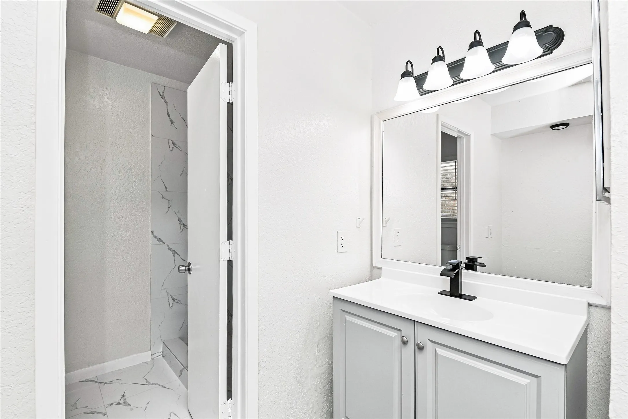 Bathroom featuring a vanity with a white countertop, light grey cabinetry, and a black faucet