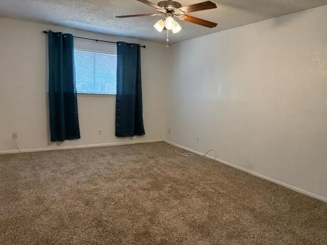 Primary Bedroom - Neutral wall color with textured finish, ceiling fan with integrated lighting, and 2 walk-in closets