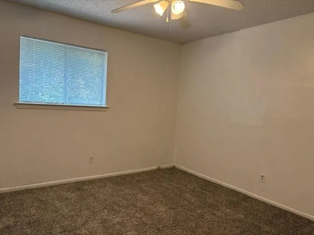 Bedroom Neutral tone wall finishes, textured carpeting, and a ceiling fan with integrated lighting