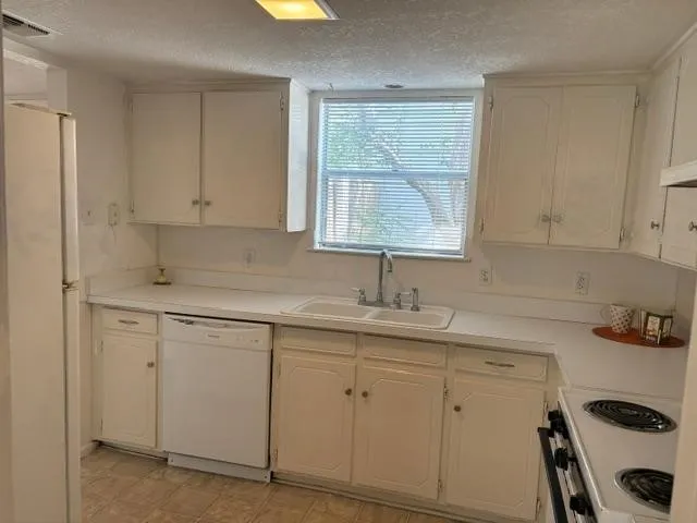 White cabinetry, white appliances, dual basin sink, white countertops, and window with blinds