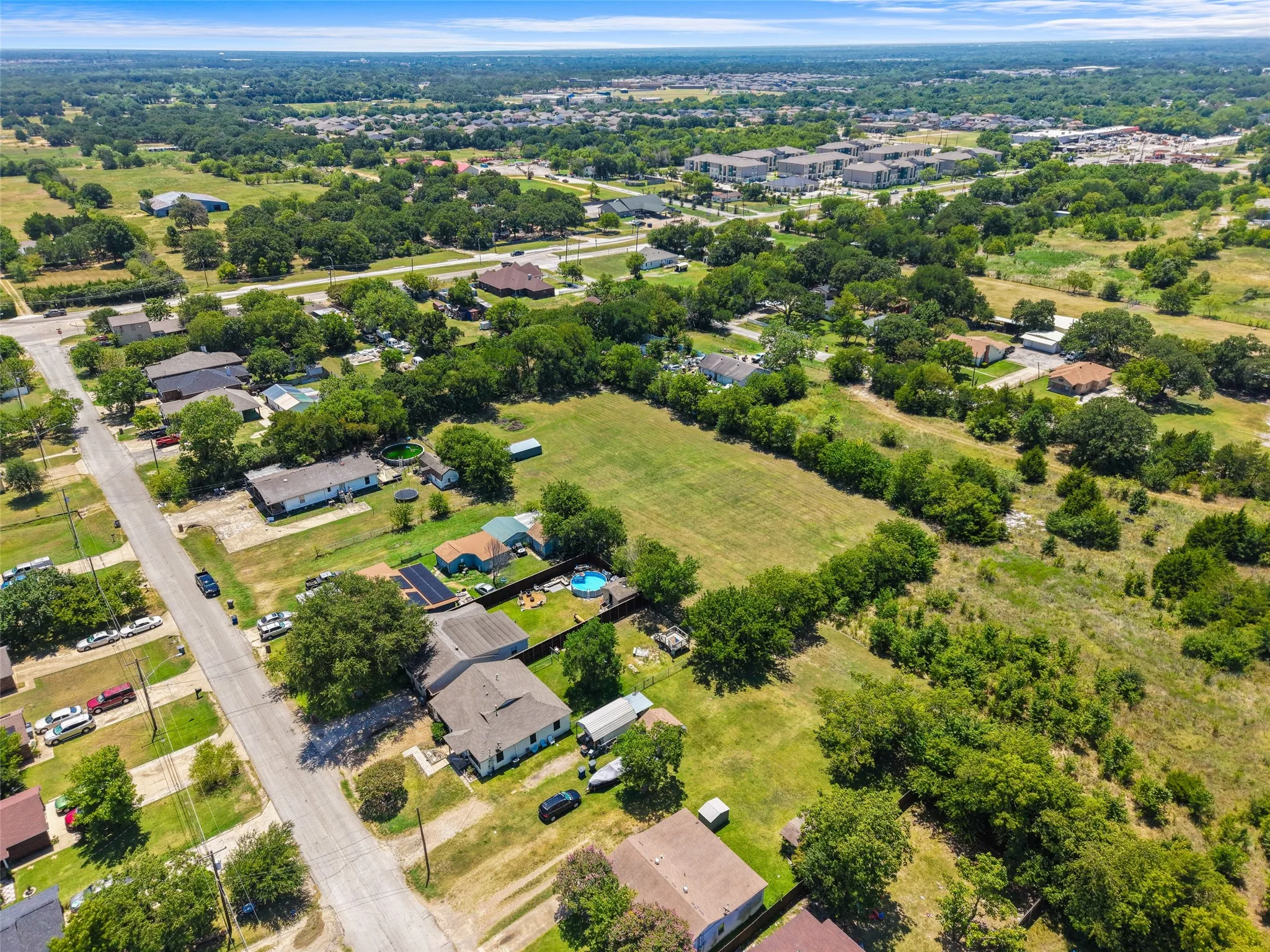 Aerial perspective showcasing expansive green spaces, residential properties, and surrounding tree coverage