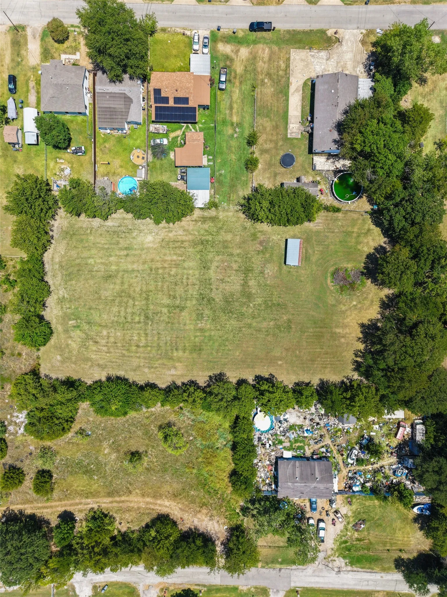Expansive grassy lot bordered by mature trees