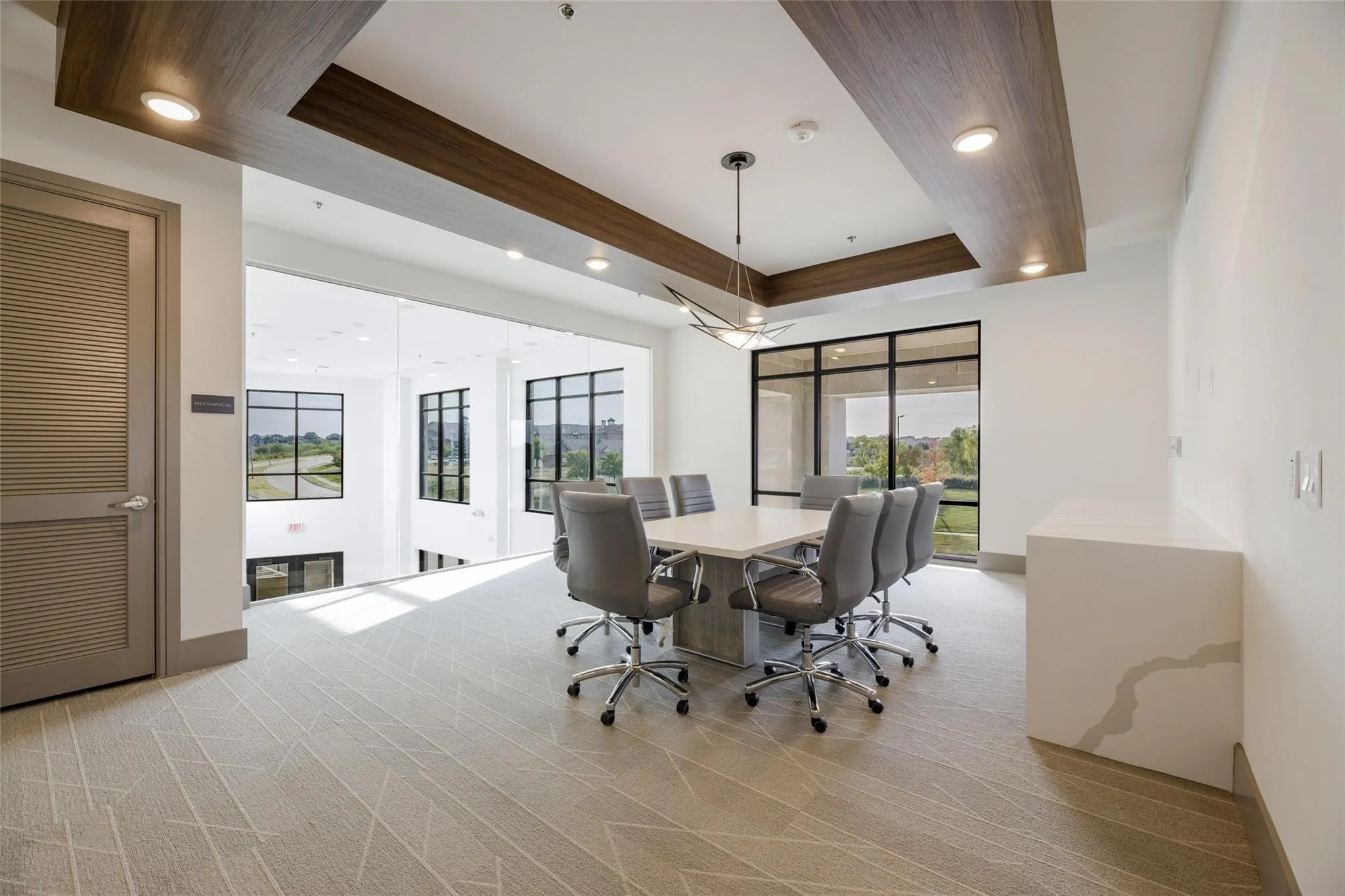 Recessed lighting, wood-finish ceiling accent, patterned carpet, expansive window, and integrated stone counter