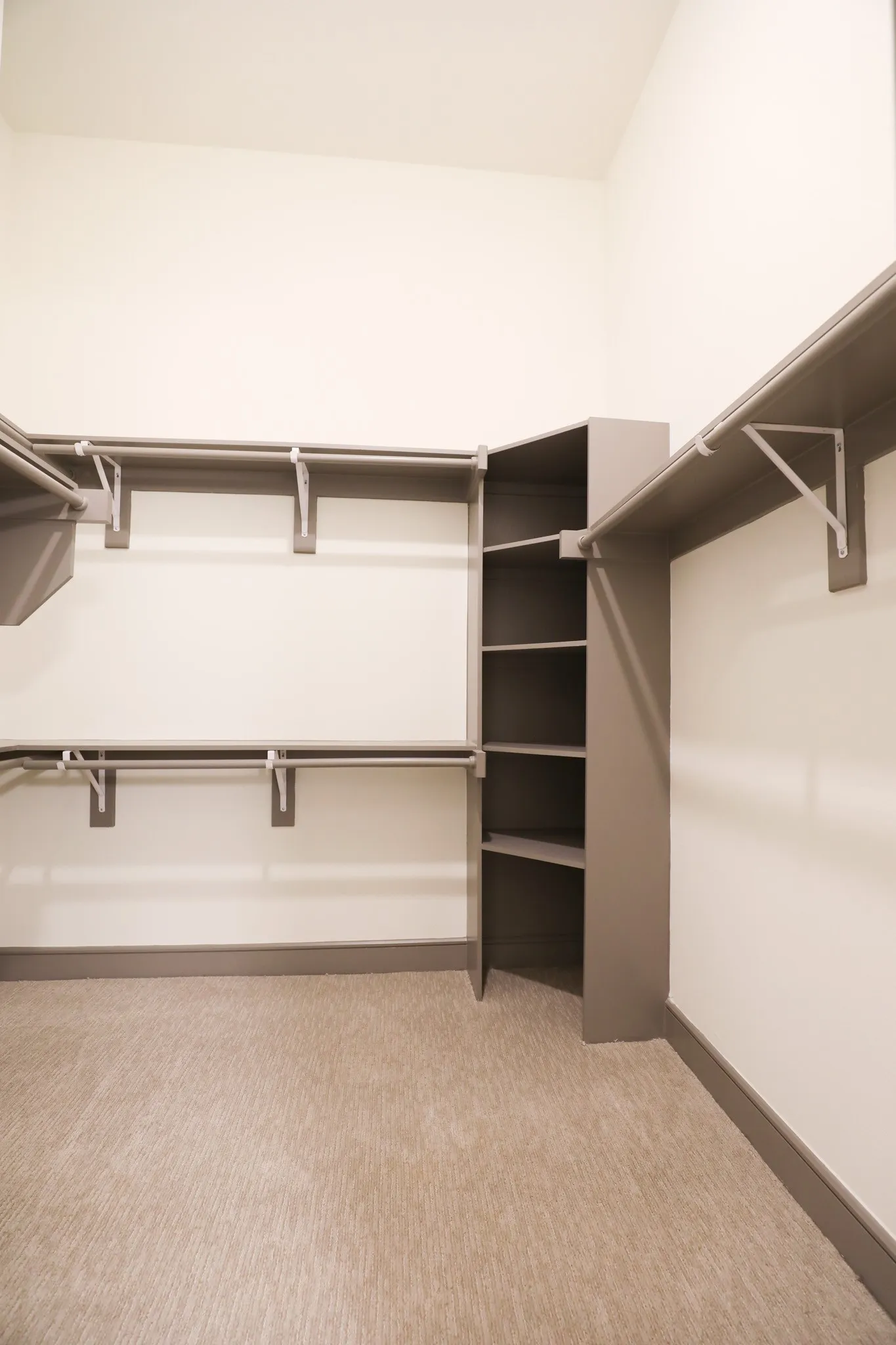 Walk-in closet with carpet flooring, built-in shelving, and multiple hanging rods