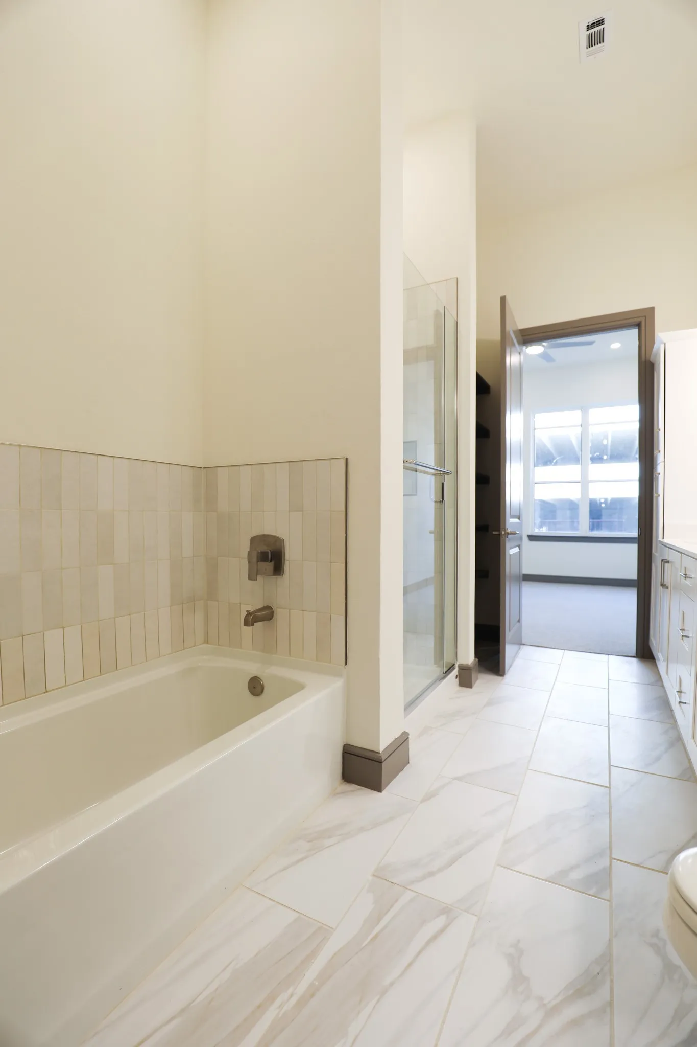 Porcelain tile flooring, built-in bathtub, tile tub surround, and glass-enclosed shower