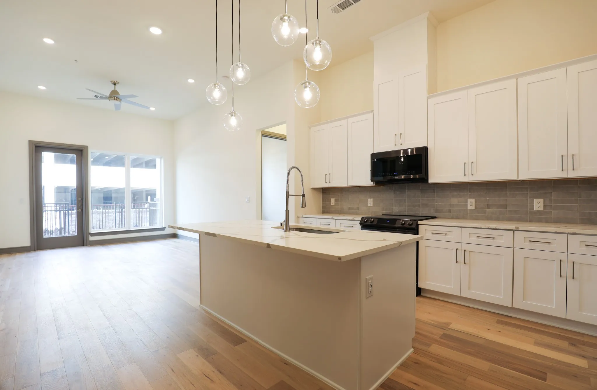 High ceilings with recessed lighting, wood-finish flooring, and pendant light fixtures