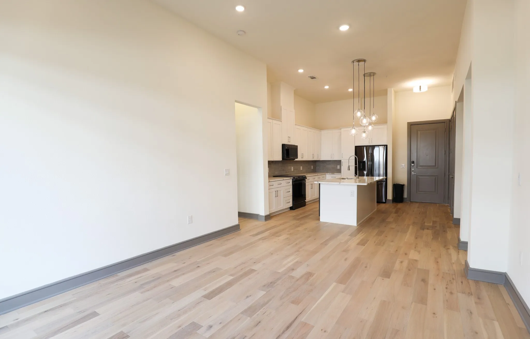 Wood-finish flooring throughout, recessed lighting, and a kitchen island with pendant lighting