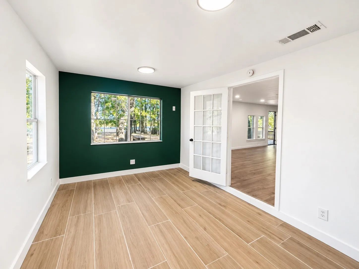 Wood-finish flooring, two windows, recessed lighting, and a frosted glass panel door