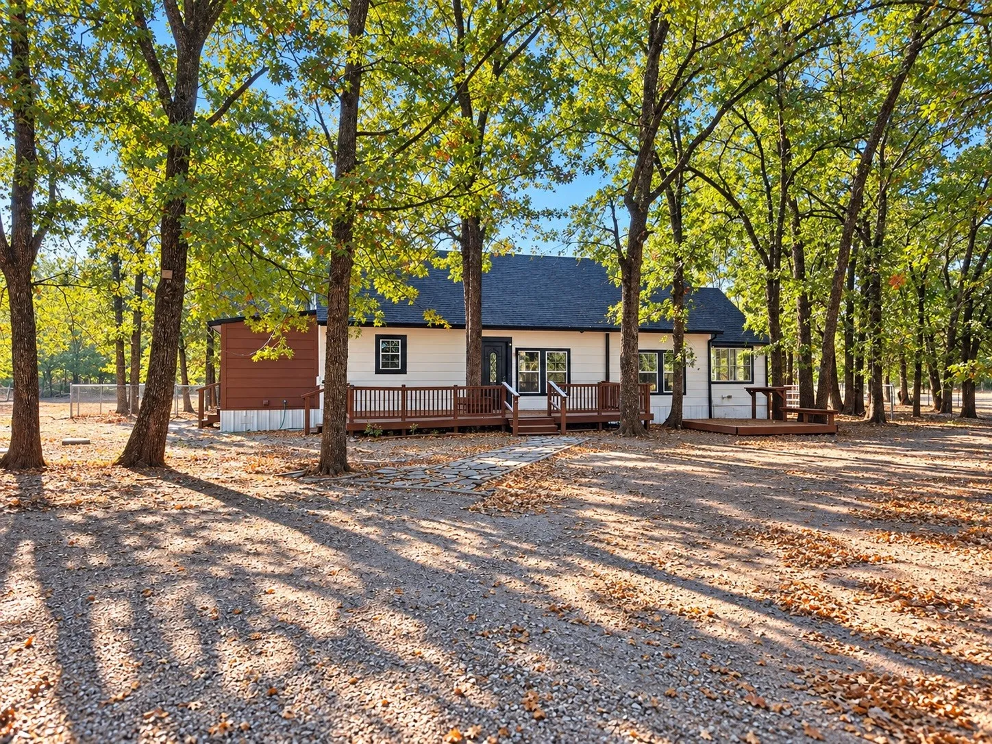 Single-story residence featuring a dark shingle roof, white siding, and dark trim windows