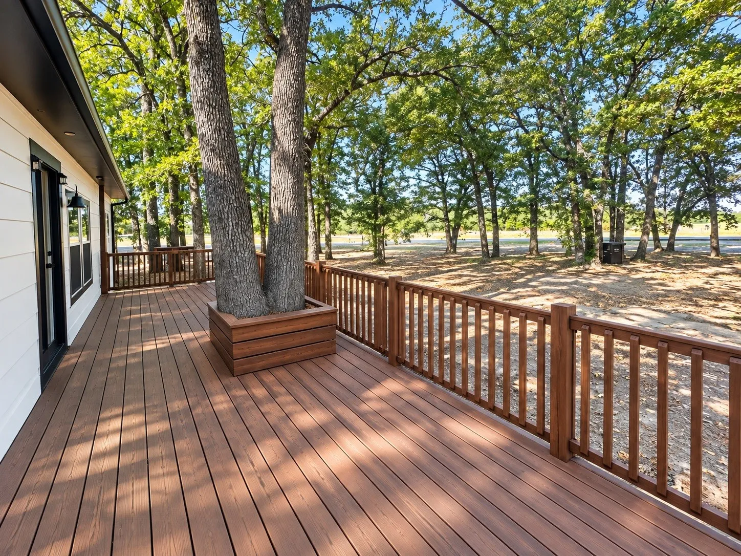 Expansive outdoor deck with wood-finish flooring, a wood railing, and a built-in planter