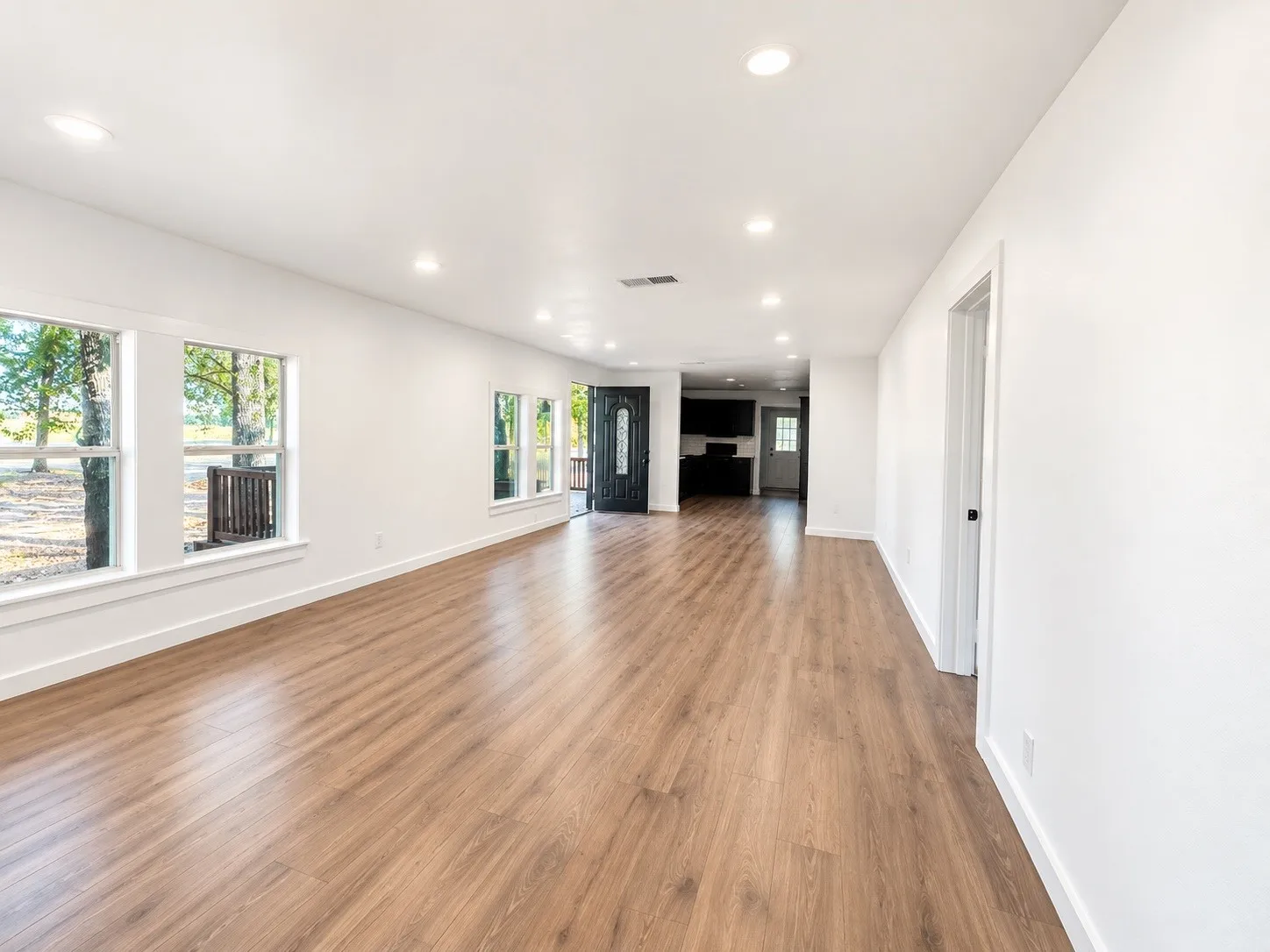 Spacious room with wood-finish flooring, recessed lighting, and multiple windows