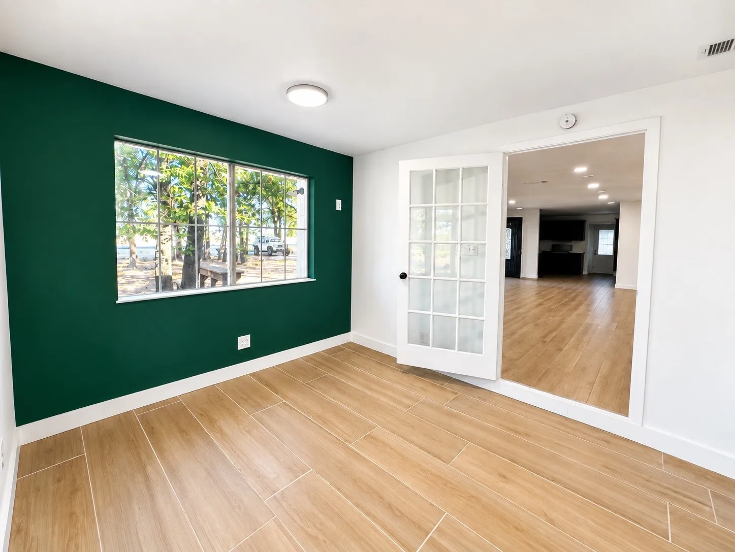 French doors with glass paneling, wood-finish tile flooring, recessed lighting, and a prominent window