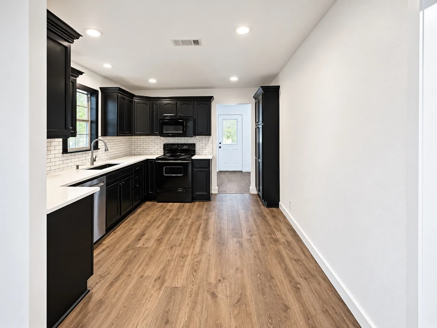 Kitchen featuring dark cabinetry, light countertops, subway tile backsplash, wood-finish flooring, and recessed lighting