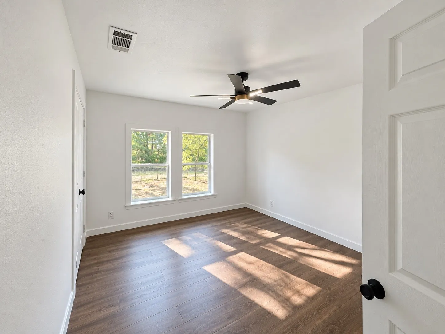 Wood-finish flooring, white walls, and a contemporary ceiling fan with integrated lighting