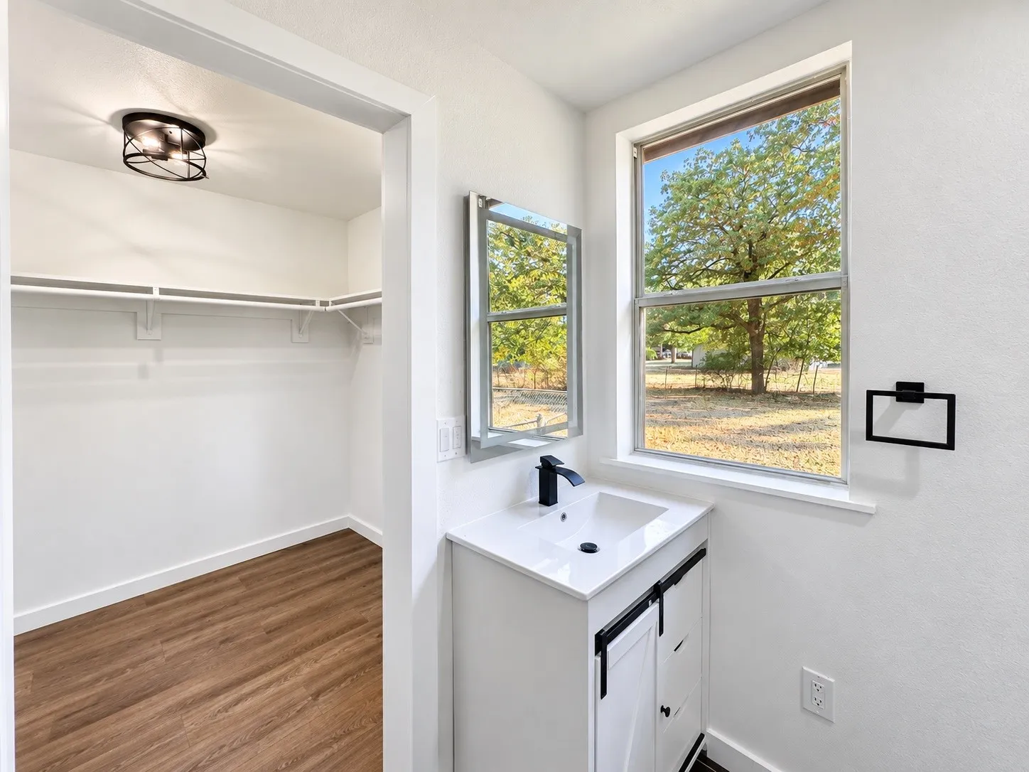 Vanity with integrated sink, white countertop, and dark-finish faucet