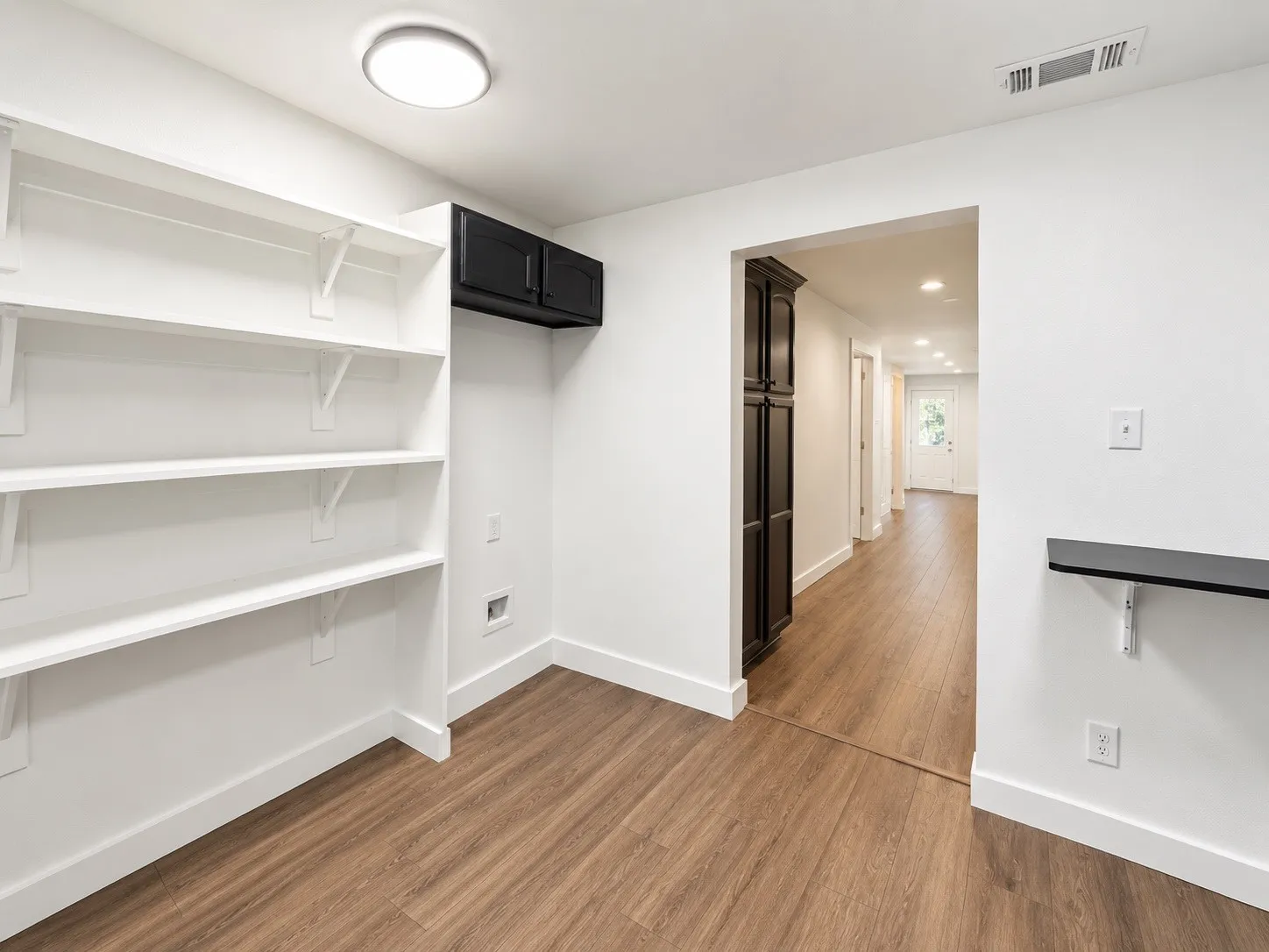Built-in shelving, dark wood-finish cabinetry, wood-finish flooring, and a flush-mount ceiling light