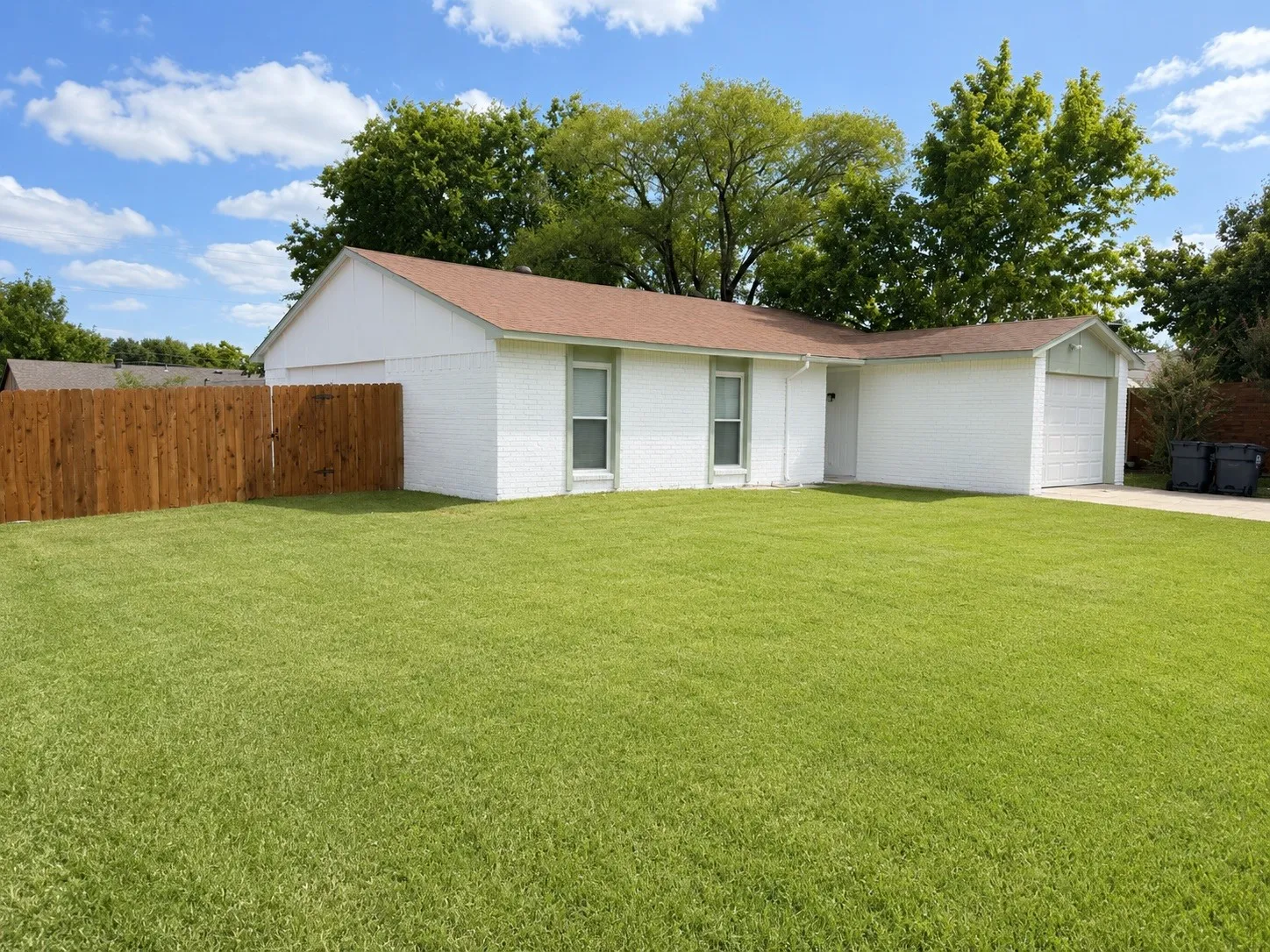 White brick residence featuring a brown asphalt shingle roof and an attached garage
