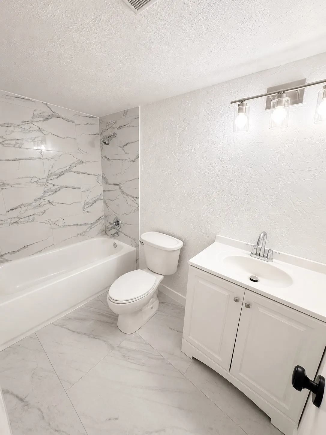 Bathroom featuring a white bathtub, toilet, and vanity with an integrated sink