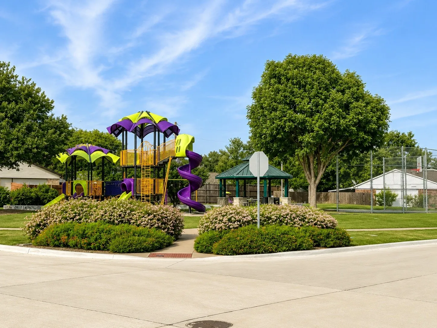 Community park featuring a vibrant multi-level playground, a shaded gazebo, and a basketball court