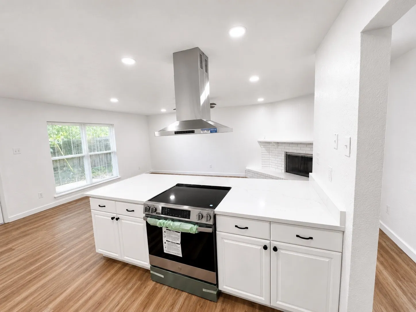 Kitchen island featuring a built-in range, white shaker-style cabinetry, and white countertops