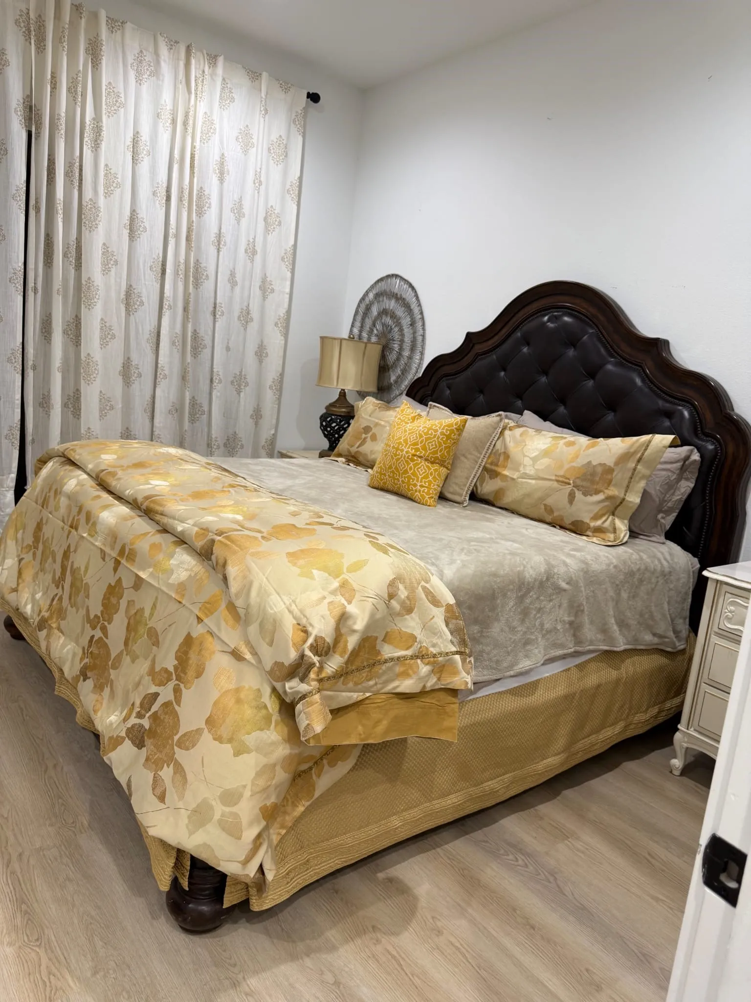 Wood-finish flooring with a dark wood-stained, tufted headboard and white walls