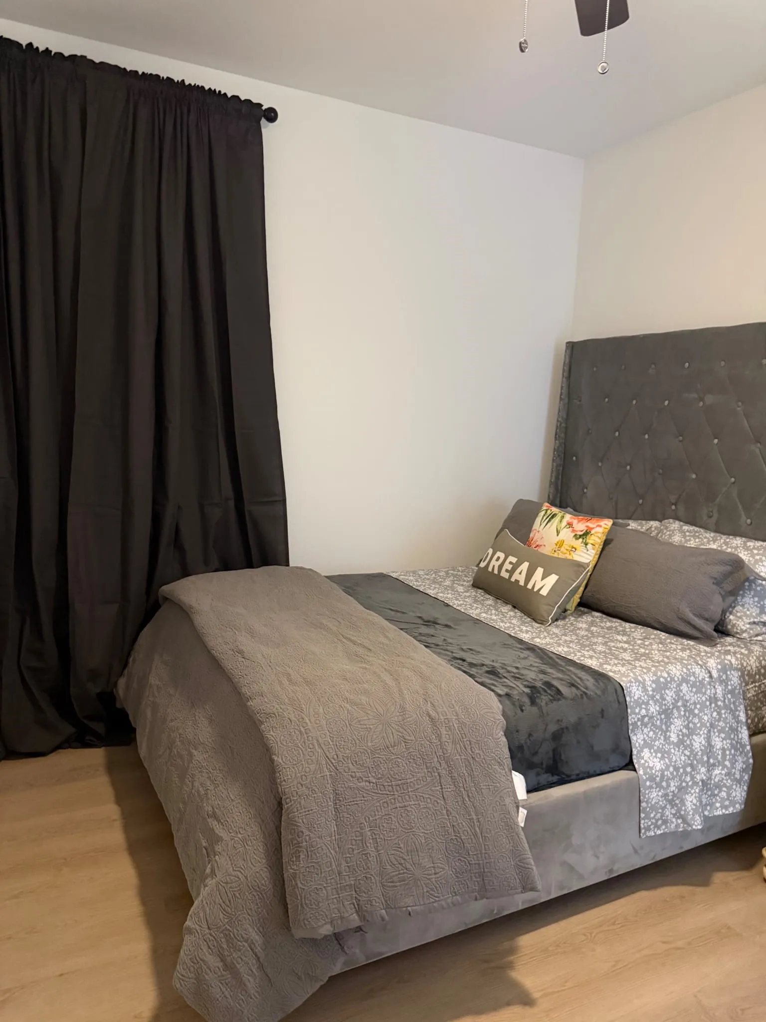 Wood-finish flooring with white walls and dark curtains