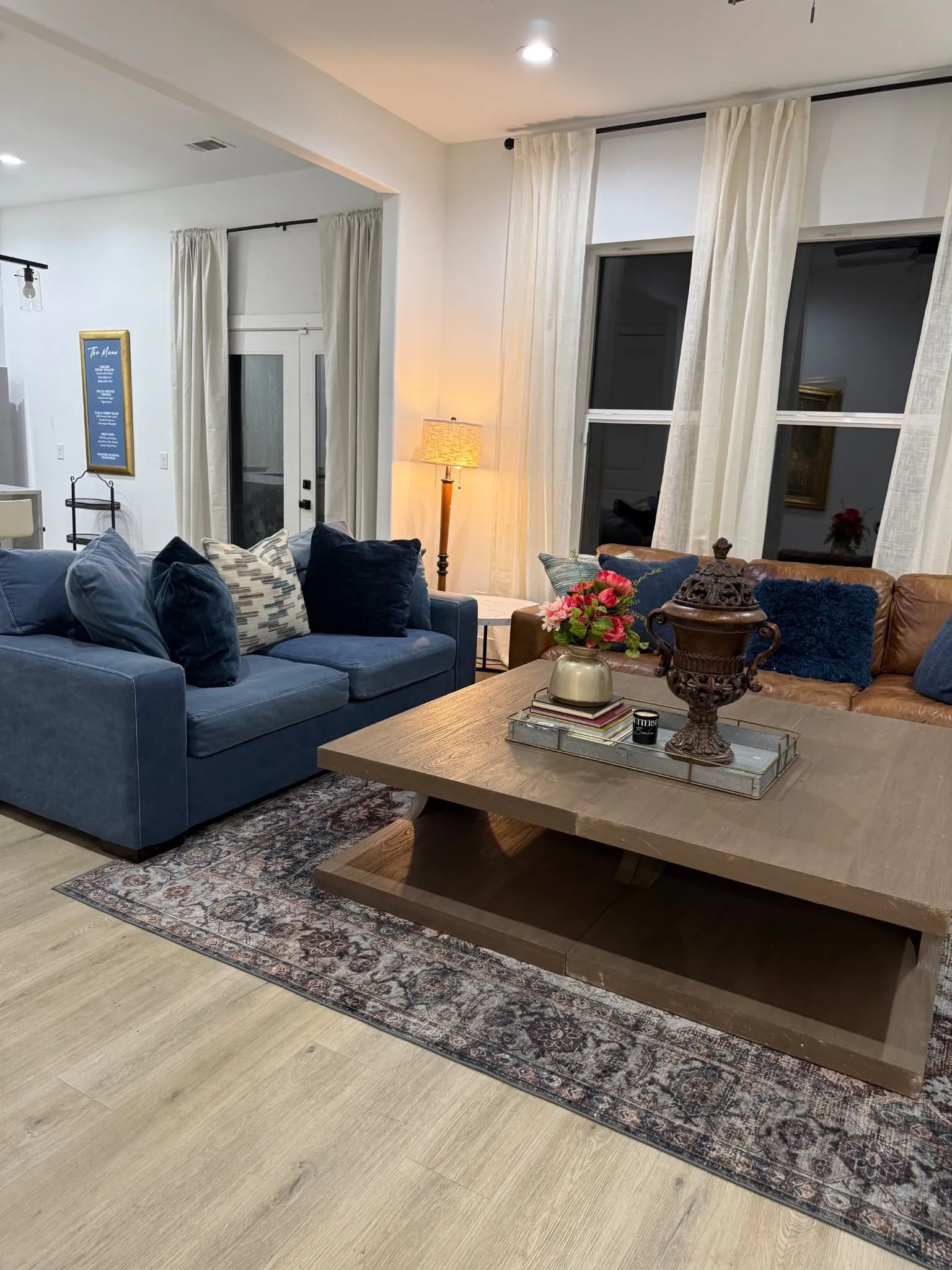 Open-concept living area featuring wood-finish flooring, recessed lighting, and large windows with roller shades