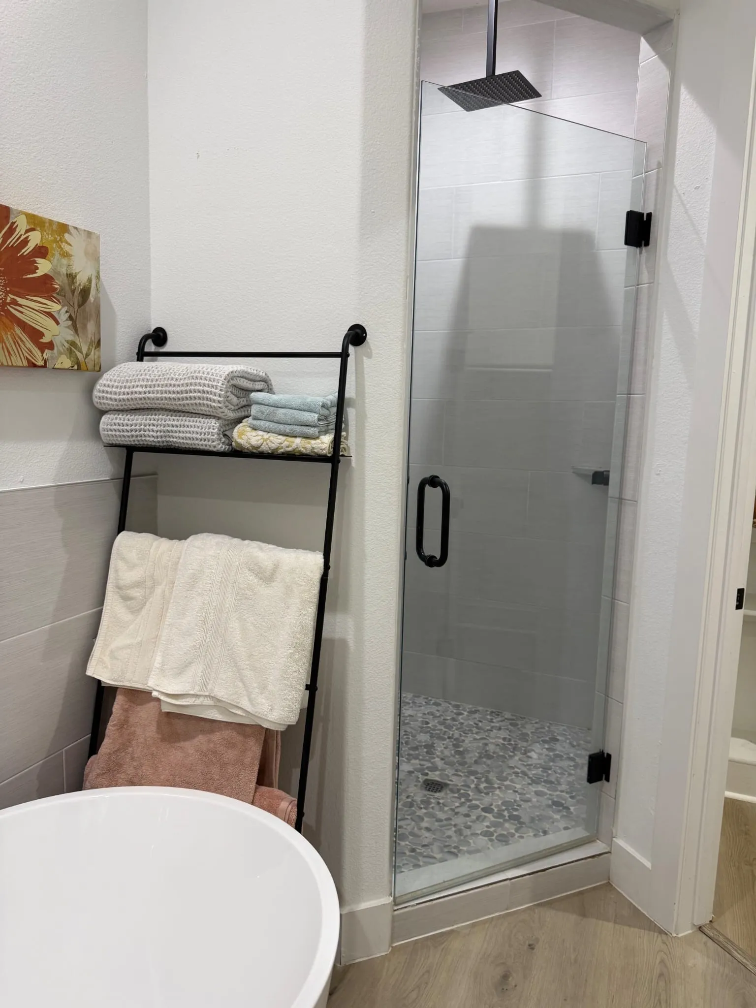 Frameless glass shower enclosure with matte black hardware, rain showerhead, and tiled walls