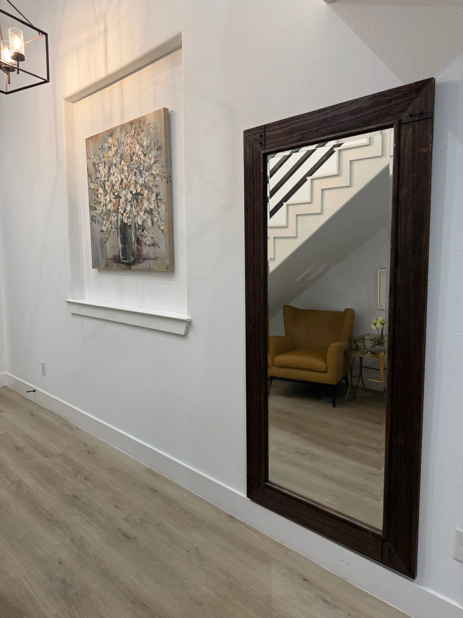 Recessed wall niche, contemporary framed mirror, wood-finish flooring, and a modern light fixture