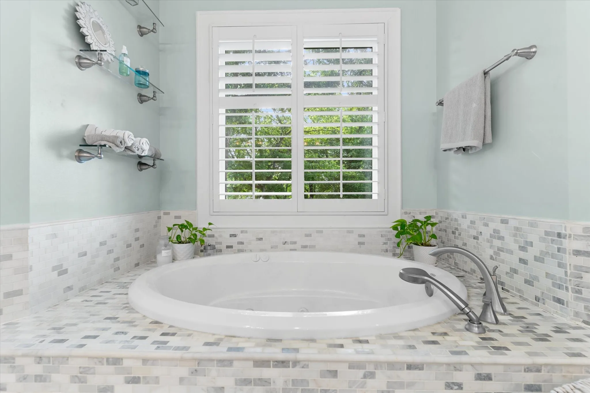 Built-in soaking tub with a deck-mounted faucet and handheld sprayer, surrounded by mosaic tile