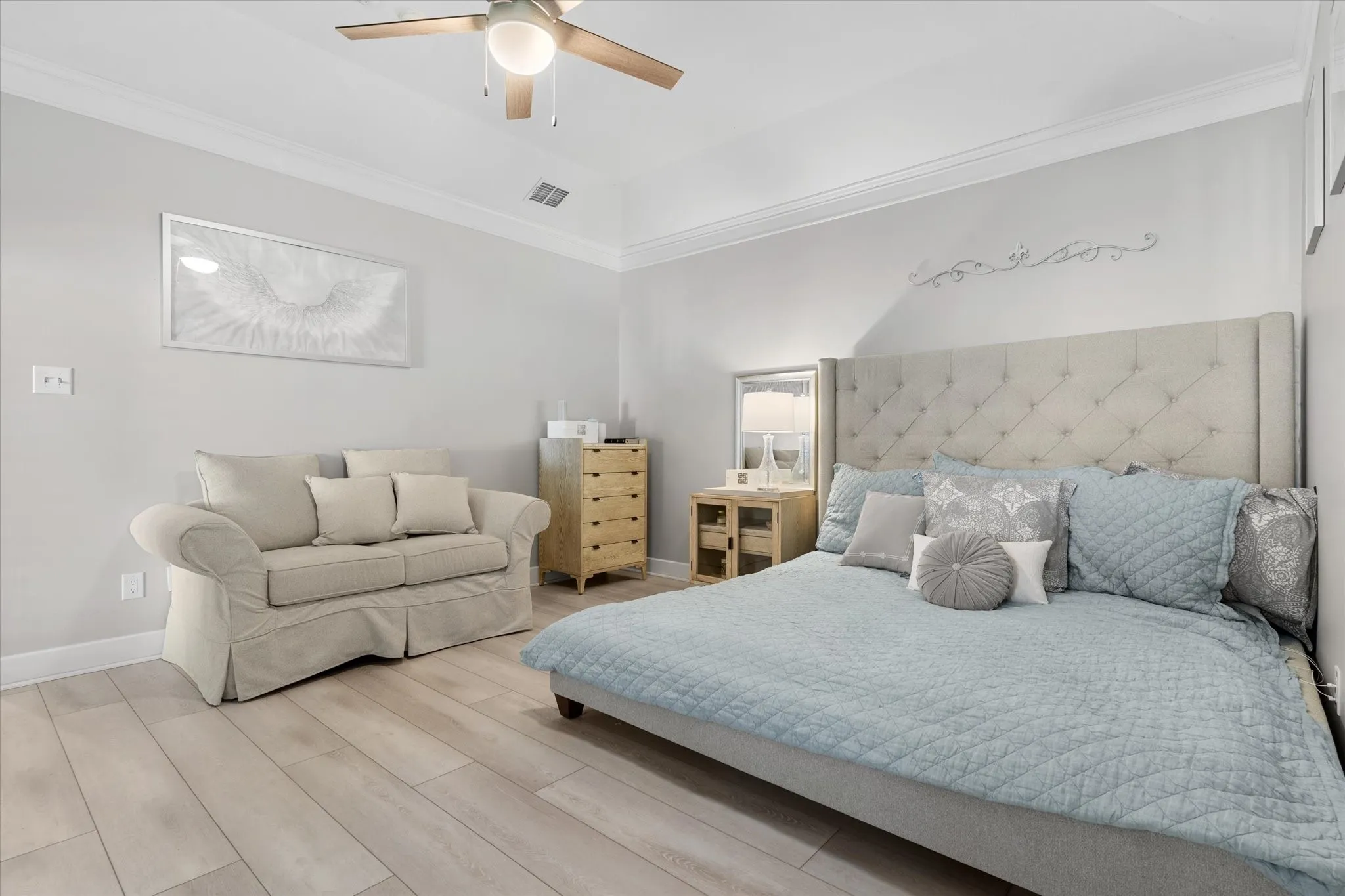 Wood-finish flooring, crown molding, a ceiling fan, and a light gray wall color