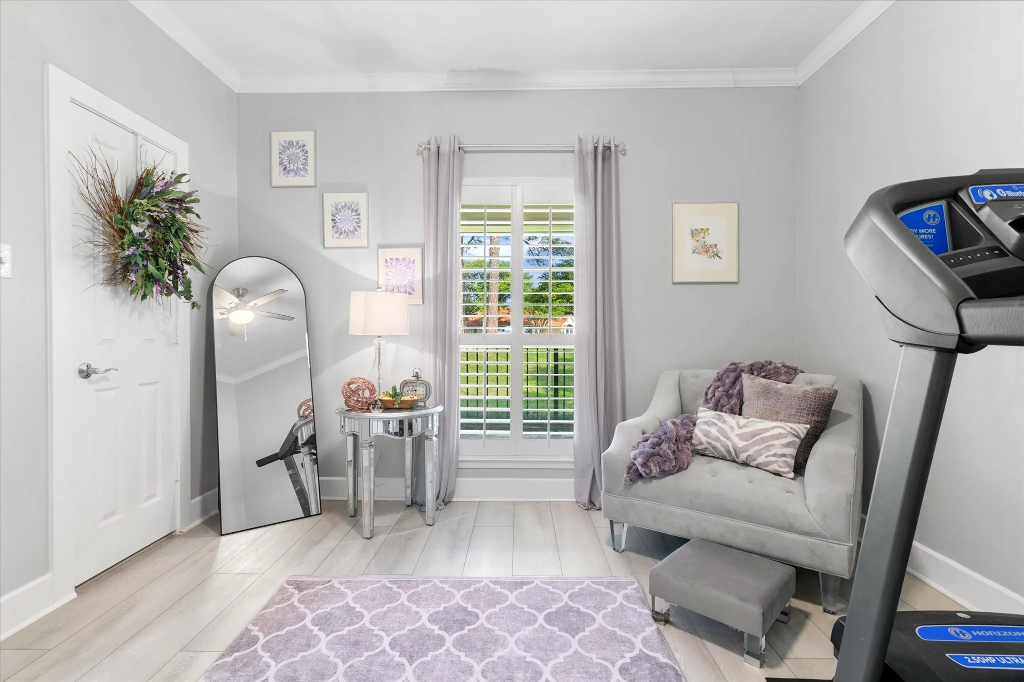 Light-toned wood-finish flooring, white trim, and a window with plantation shutters