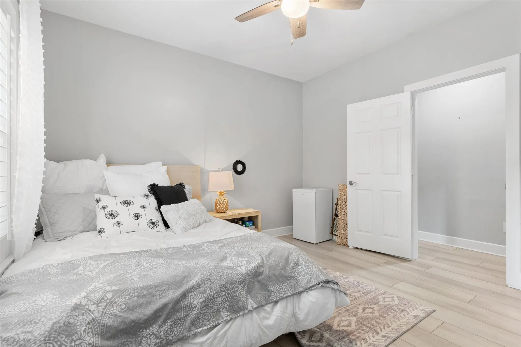 Light wood-finish flooring, a ceiling fan with light fixture, and a white paneled door
