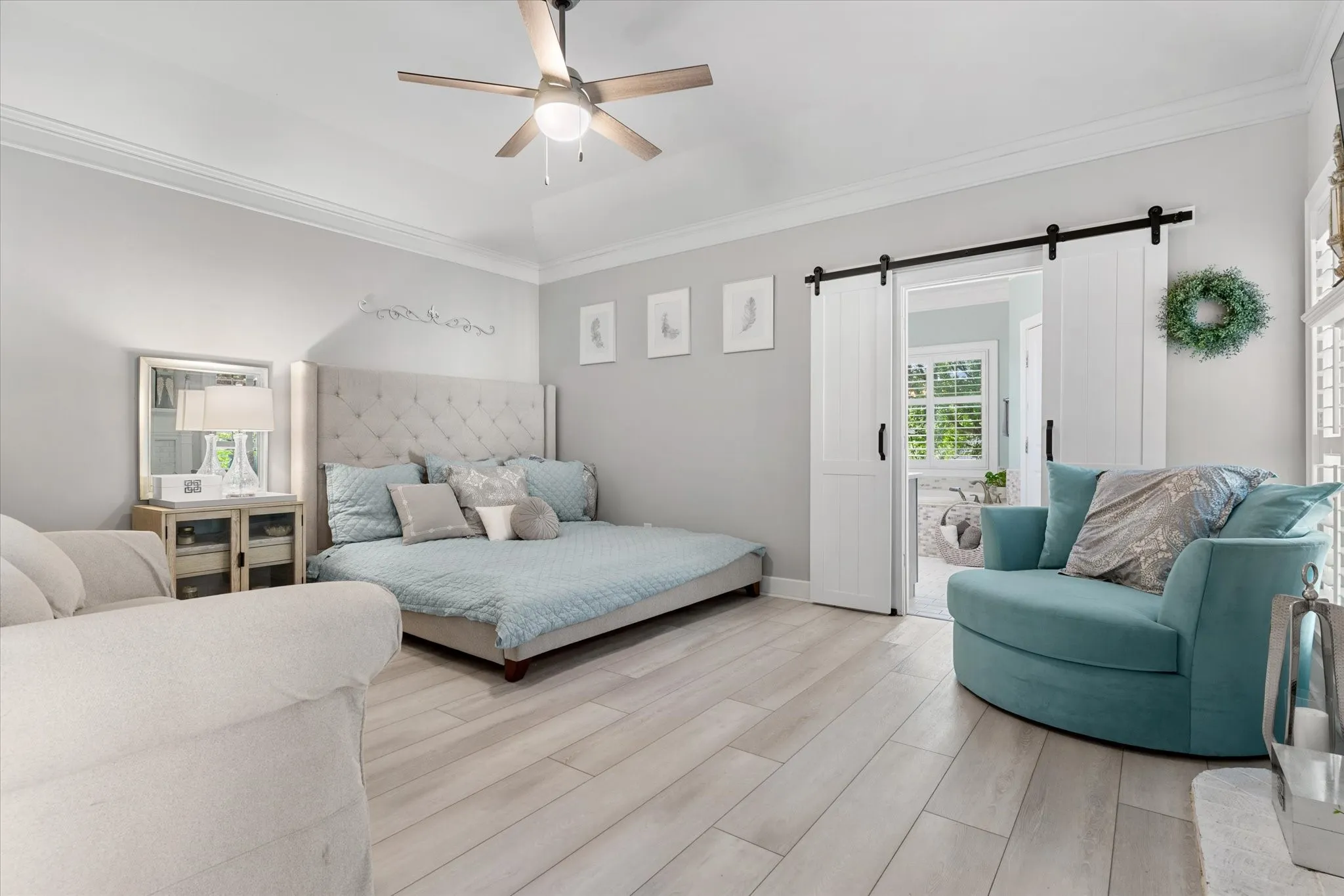 Vaulted ceiling featuring a ceiling fan with integrated lighting, crown molding, wood-finish flooring, and white barn doors with black hardware