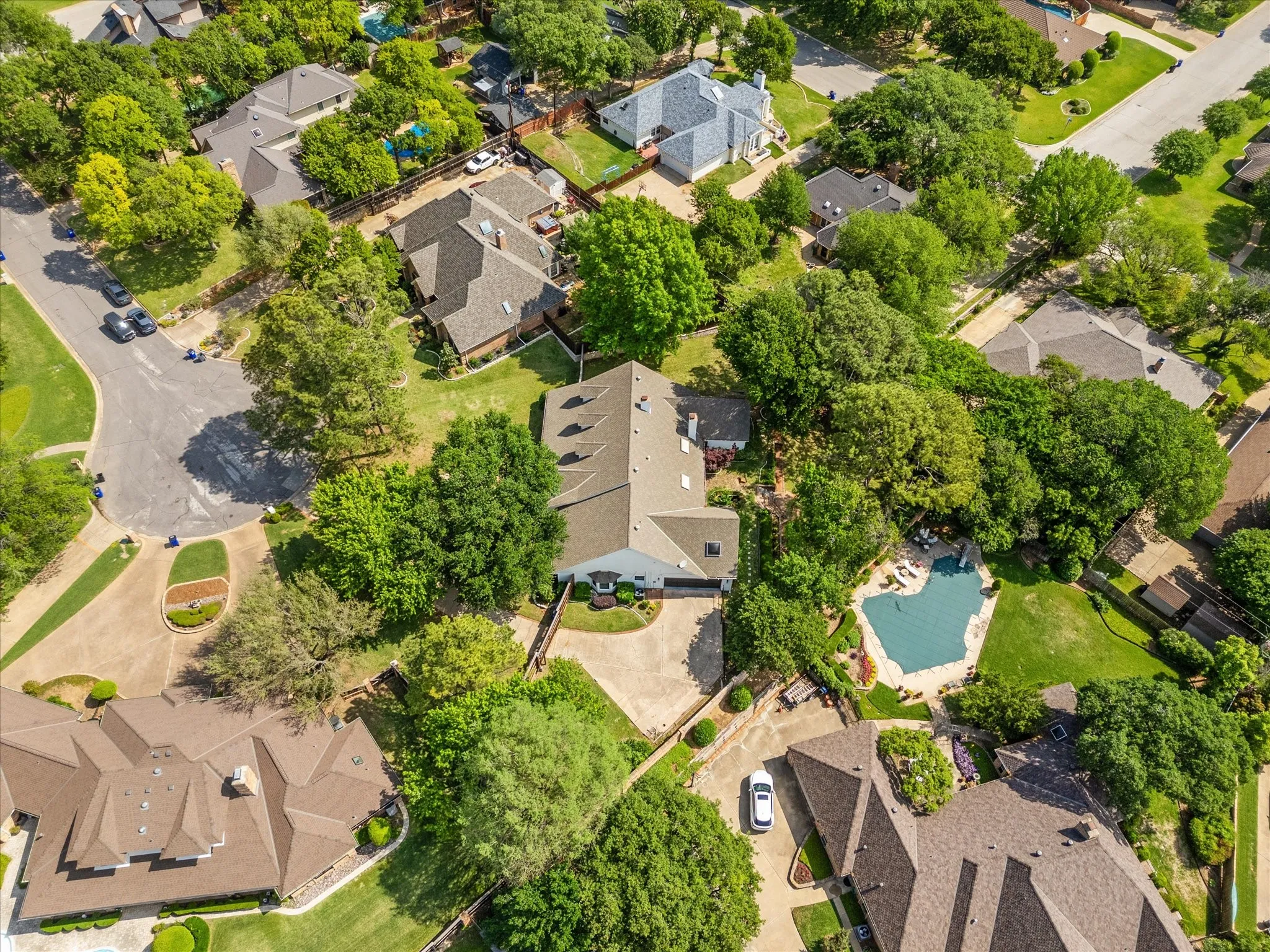 Lush landscaping surrounds the property, featuring a private swimming pool with integrated spa and a multi-level roofline