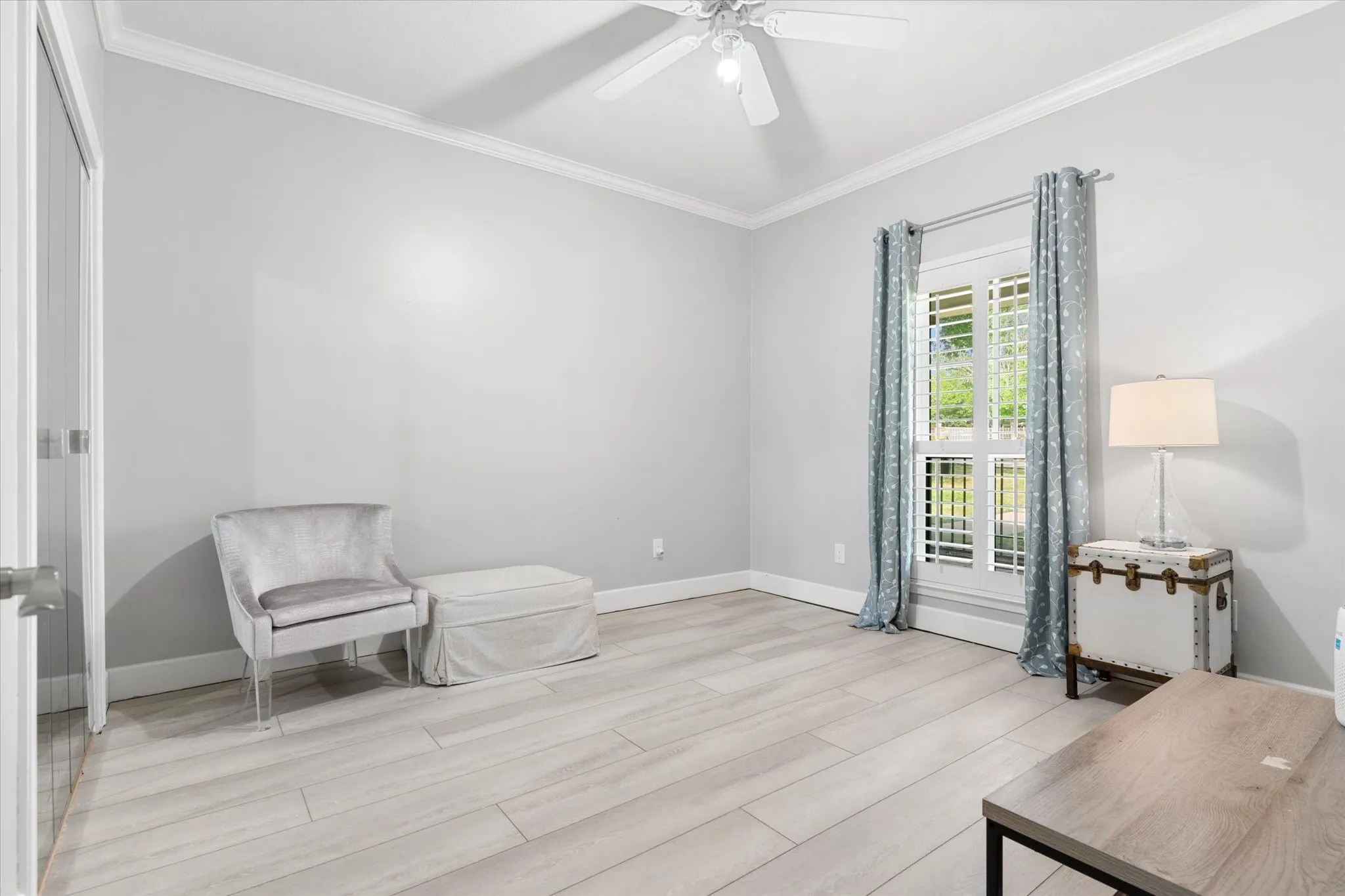 Light wood-finish flooring, crown molding, and a ceiling fan with integrated lighting