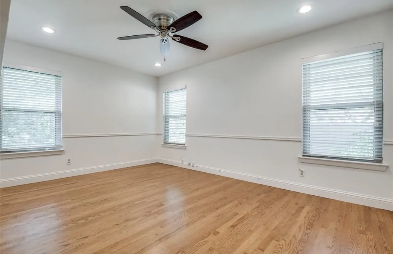 Wood-finish flooring, recessed lighting, ceiling fan, and multiple windows with blinds