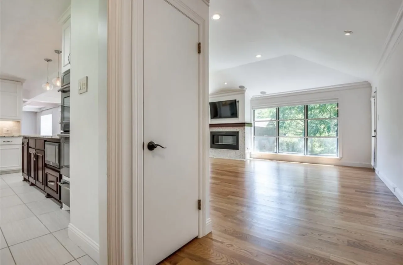 Hardwood flooring, vaulted ceiling, recessed lighting, corner fireplace with tile surround, and large window