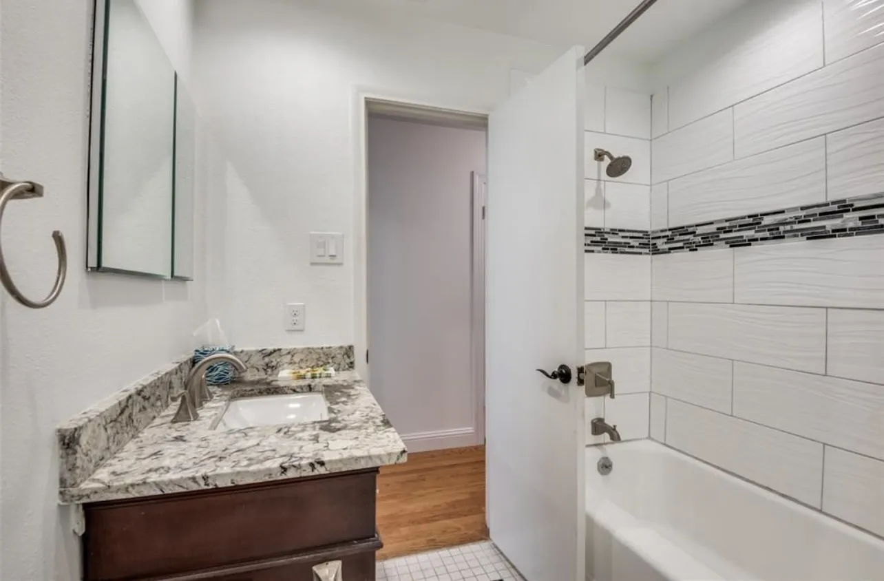 Bathroom featuring a single vanity with a granite countertop, undermount sink, and brushed nickel faucet