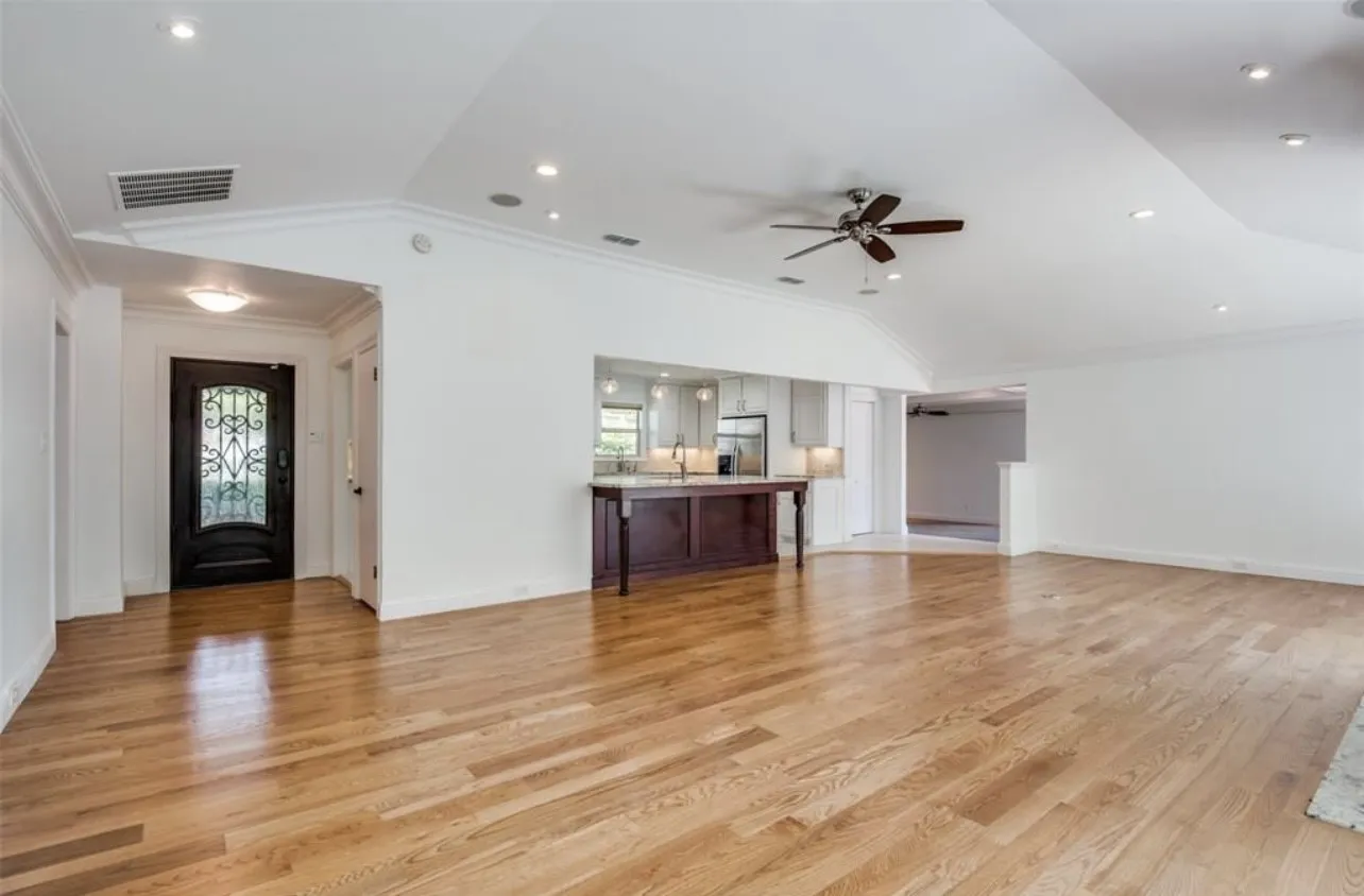 Hardwood flooring throughout, recessed lighting, ceiling fan, and a kitchen pass-through with a breakfast bar