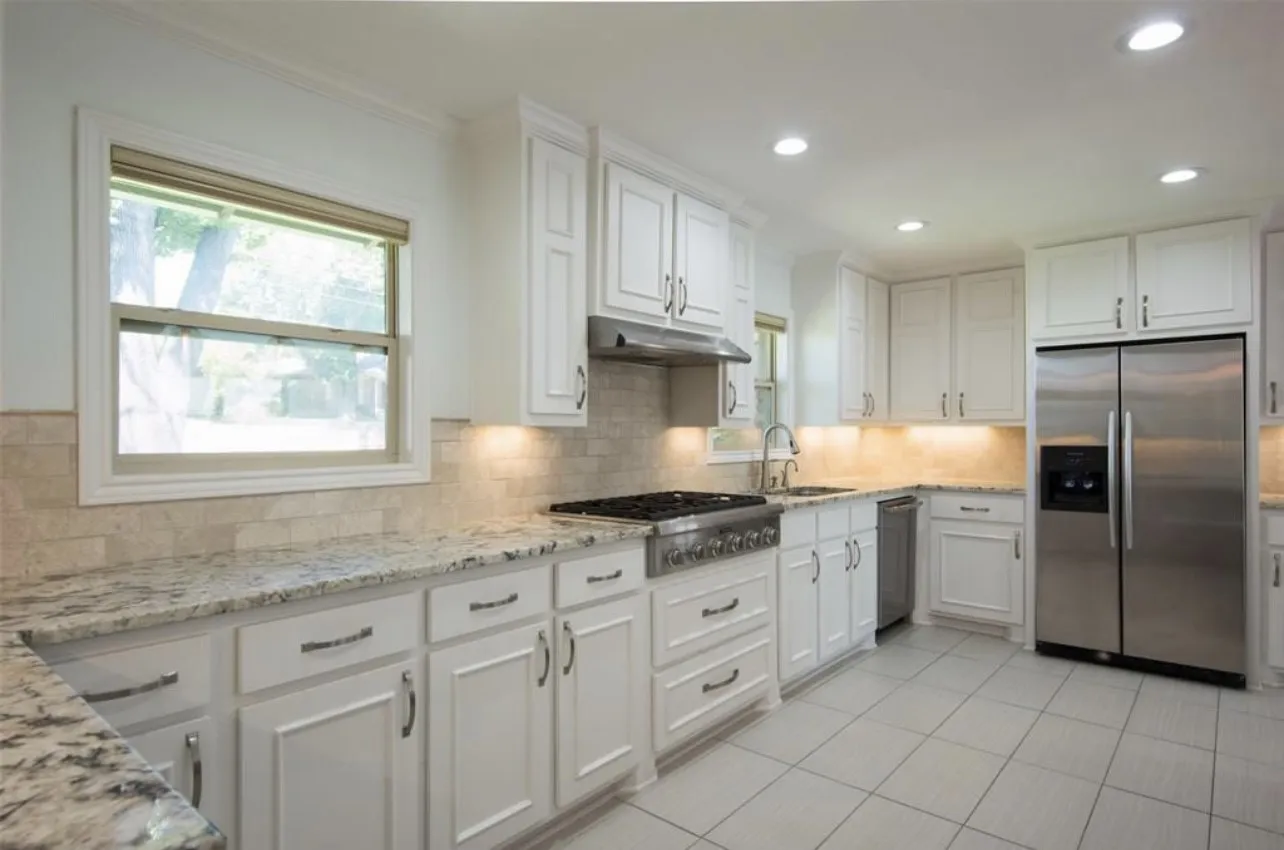 White cabinetry with integrated stainless steel appliances and a dual-basin sink