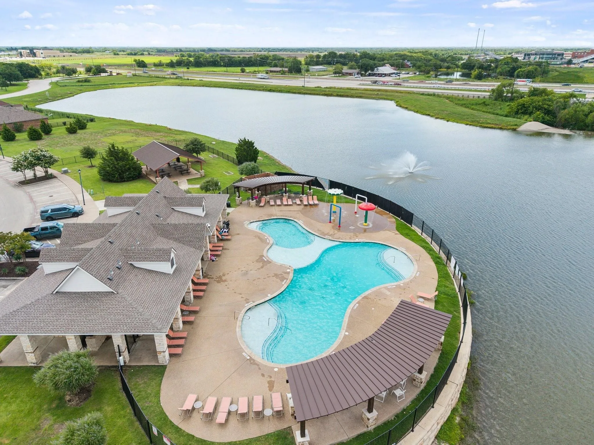 Community pool with integrated water features, adjacent to a large body of water