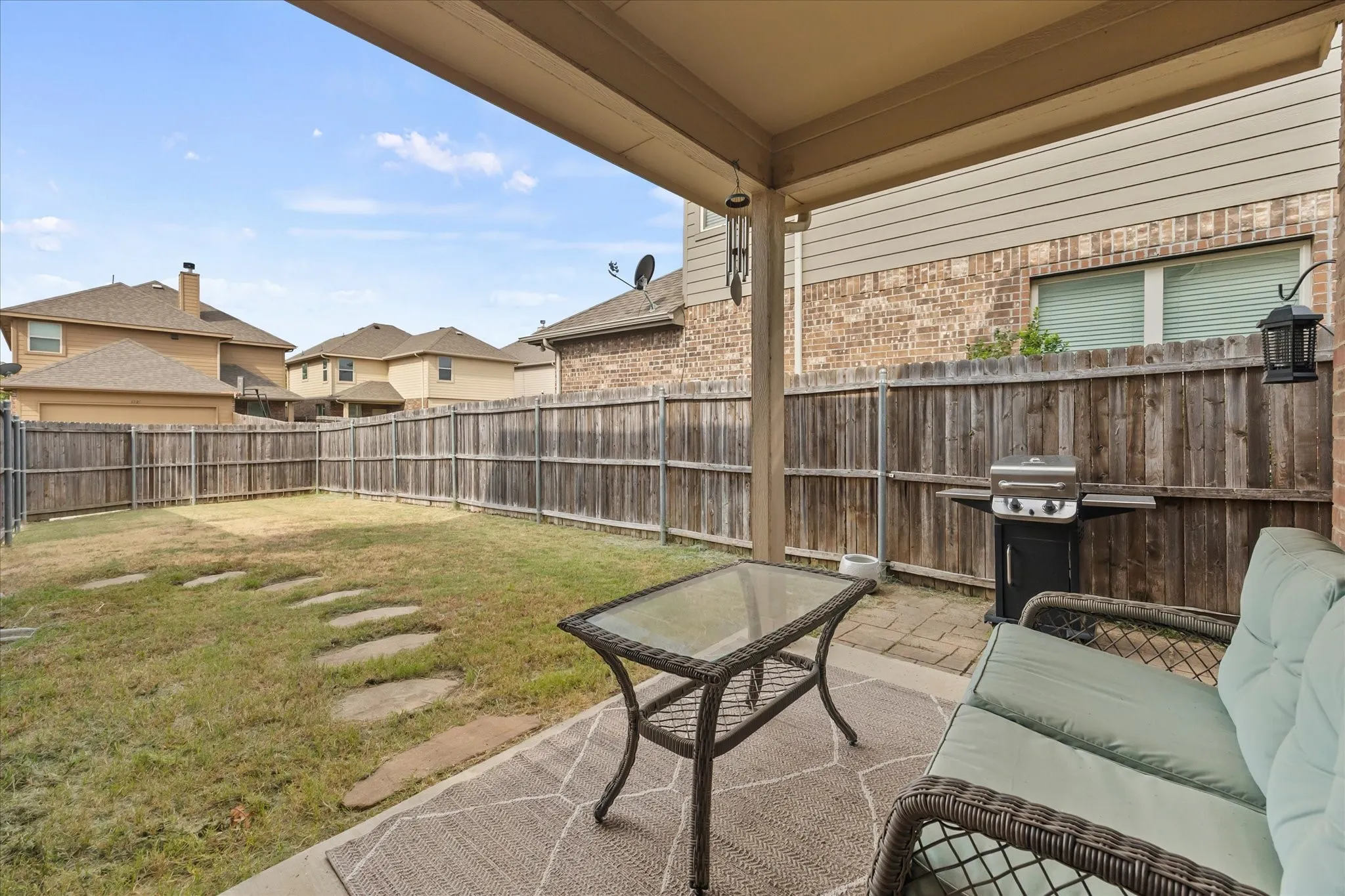 Covered patio with concrete flooring, wood privacy fence, and stepping stone path