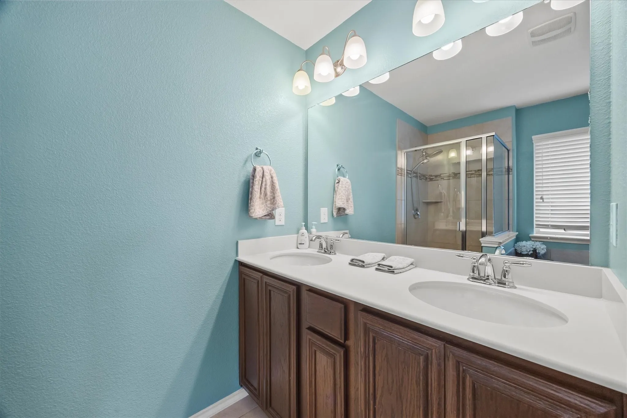 Dual vanity with integrated sinks, chrome faucets, and wood-finish cabinetry